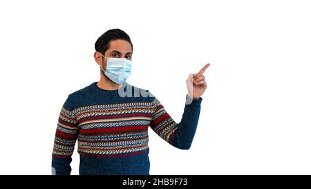 Caucasian man pointing with one hand and finger to the side and using sterile face mask isolated on white background studio. Guy showing things at qua Stock Photo