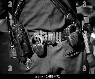 Police officers wearing belts equipped with handguns, handcuffs, radio, baton and other policing equipment. Stock Photo