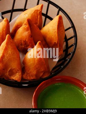 Indian snack punjabi samosa in close up with mint chutney or sauce, potato stuffed deep fried pastry Stock Photo