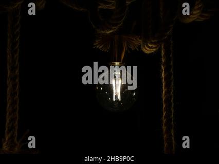 Dirty old light bulb on ropes Stock Photo