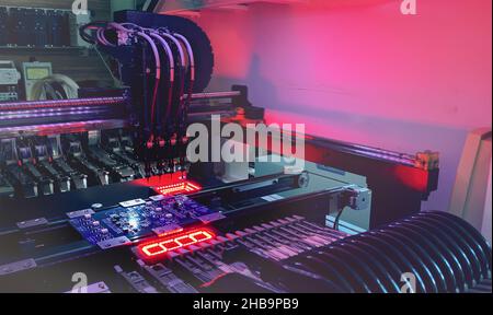 SMD Assembly of electronic components on a motherboard by an automated Pick and Place robot. Technology for SMD assemblage of chips with artificial intelligence. Stock Photo