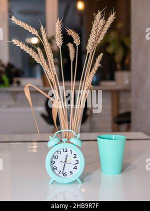 Home interior in detail, decorations on the kitchen table, retro clock, wheat spikelets on the kitchen table Stock Photo