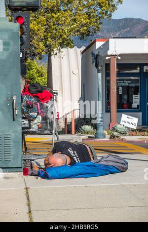 A homeless man sleeping on the sidewalk Stock Photo