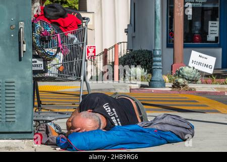 A homeless man sleeping on the sidewalk Stock Photo