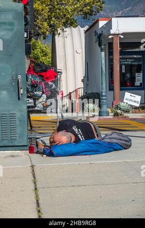A homeless man sleeping on the sidewalk Stock Photo