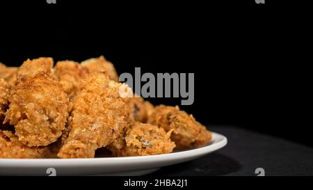 Cool beautiful fresh juicy cooked chicken wings in breading. Buffalo wings spread on food in white plate. Cooking with deep fryer fry machine. Stock Photo