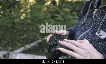 Traveler photographing scenic view in forest. One caucasian woman shooting close up look. Girl take photo video on dslr mirrorless camera. Stock Photo