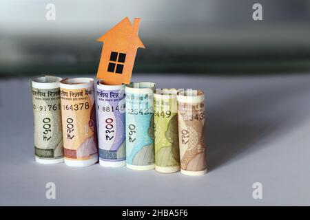 Indian currency notes with 2D paper model home with key, Save money for Future home plan, Real estate business concept Stock Photo