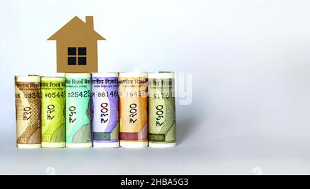 Indian currency notes with 2D paper model home, Save money for Future home plan, Home loan concept Stock Photo