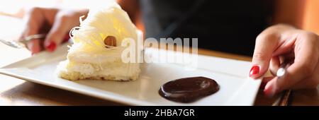 Woman is sitting in cafe on plate of sweet cake with liquid chocolate Stock Photo