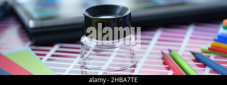 Magnifier pencils and color palette swatches on table Stock Photo