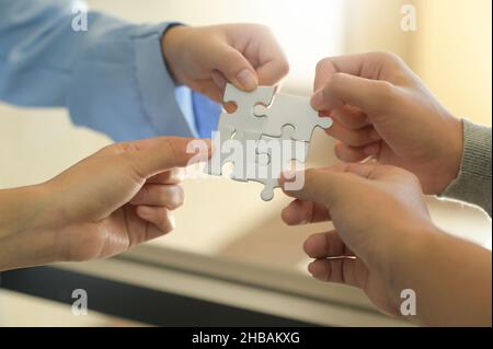 Group of businessmen holding white jigsaw puzzle pieces, group of people putting together jigsaw puzzles, problem solving concept, teamwork concept. Stock Photo