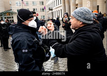 Berlin, Germany. 18th Dec, 2021. A participant of the banned demonstration of opponents of the Corona Rules stretches his fists towards a policeman. The demonstration had been banned by the Berlin police. Credit: Fabian Sommer/dpa/Alamy Live News Stock Photo