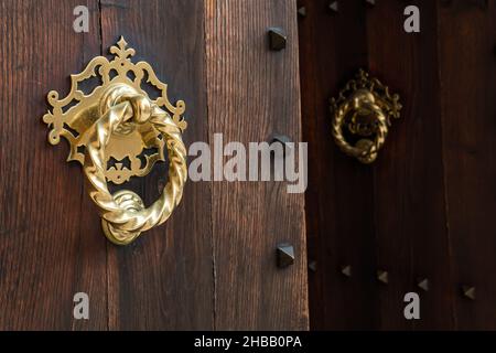 Close-up of a gilded metal knob on an open rustic wooden door Stock Photo