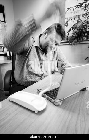 JOHANNESBURG, SOUTH AFRICA - Aug 09, 2021: An angry man frustrated with broken laptop in grayscale Stock Photo
