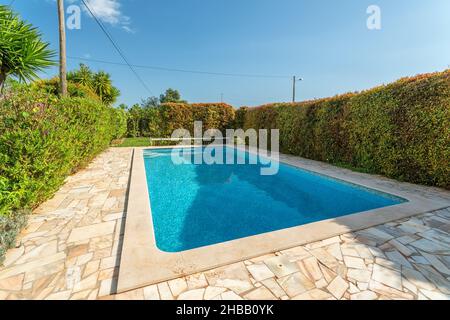 Rectangular swimming pool in typical Mediterranean architecture in the garden in summer. For tourists Stock Photo