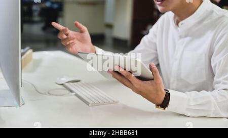 Young man holding digital tablet and video conferencing with a computer for the online meeting from home, work from home, work online. Stock Photo