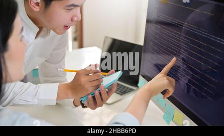 Male program analyst examining programs with female programmer on computer screen,Computer concepts. Stock Photo
