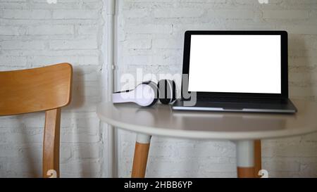 Mockup Laptop blank screen and headphone on placed on a table in a cafe. Stock Photo