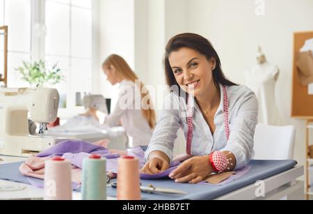 Portrait of woman dressmaker, fashion designer, tailor or seamstress at work in studio. Stock Photo