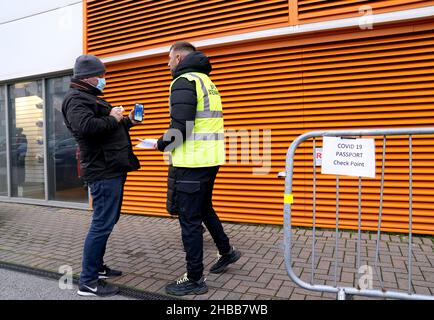 *EDITORS NOTE: This image has been pixelated to ensure the QR code is not visible* A fan shows their Covid pass to a member of security staff at the Covid 19 passport check point ahead of the Sky Bet Championship match at Bloomfield Road, Blackpool. Picture date: Saturday December 18, 2021. Stock Photo