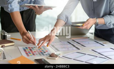 A professional smartphone application design team is designing a new project in a modern office. Stock Photo