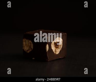 Roasted hazelnuts in dark chocolate, chocolate sweet on black background Stock Photo