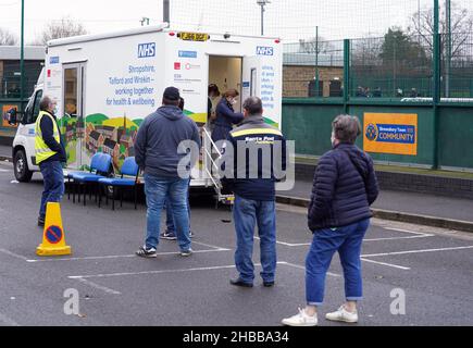 People queue at a mobile vaccination bus outside Montgomery Waters Meadow stadium in Shrewsbury, as the coronavirus booster vaccination programme is ramped up to an unprecedented pace of delivery, with every eligible adult in England being offered a top-up injection by the end of December. Picture date: Saturday December 18, 2021. Stock Photo