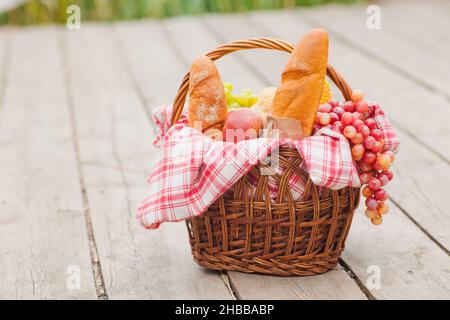 French provincial picnic. Retro style picnic basket with food on wooden pier at the lake outdoor Stock Photo