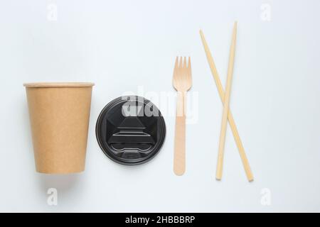 Eco-friendly cutlery. Chinese chopsticks, wooden forks, craft paper cup on white background. Minimalism eco concept.Top view Stock Photo