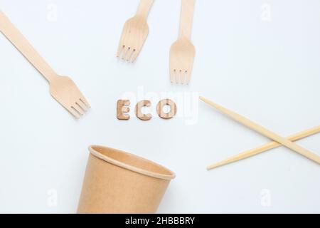 Disposable tablewar of natural materials. Eco friendly concept. Wooden forks, empty craft coffee cup, chopstick on a white background. Top view Stock Photo