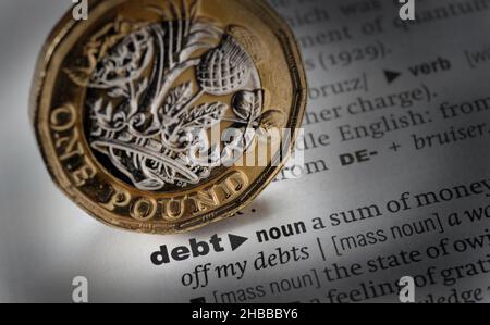 DICTIONARY DEFINITION OF THE WORD DEBT WITH ONE POUND COIN RE MORTGAGES ECONOMY HOUSEHOLD BILLS ETC UK Stock Photo