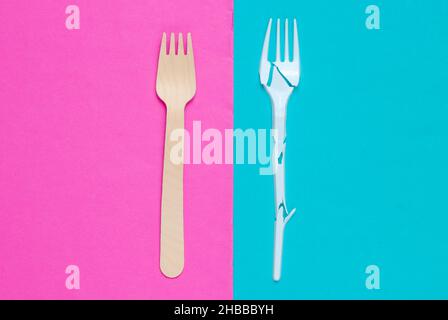 Minimalistic ecologically clean still life. Pop Art. Broken plastic fork and wooden fork on blue pink background. Cutlery made from natural materials, Stock Photo