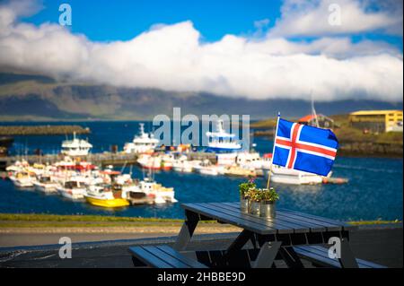 Flag of Iceland placed on a restaurant table with a harbor in the background Stock Photo