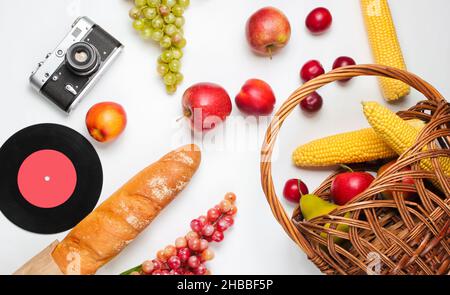Picnic setting with camera, basket, fruit, baguette on white background. Retro style junket. Stock Photo