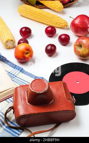 French retro style picnic. Basket with fruits and vegetables, retro camera, book,  baguette and other picnic food white background. Studio shot Stock Photo
