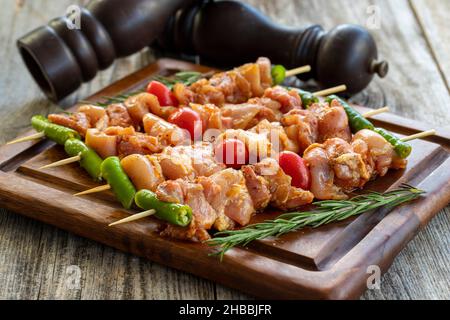 Chicken skewers on a wooden background. Close-up of raw chicken skewers marinated in tomato sauce. Horizontal view Stock Photo