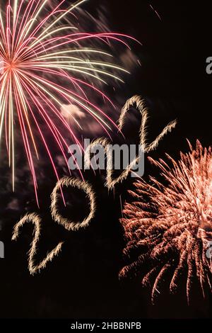 Happy New Year 2022. Sparkling burning numbers Year 2022 with firework on black background. Stock Photo