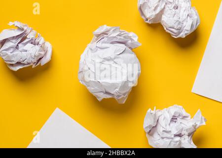 Balls of crumpled paper and white sheets of paper in the form of triangles, with space for text. Yellow background. Copy space.  Stock Photo