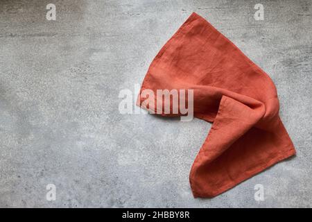 Folded linen napkin terracotta color on gray concrete table with copy space, top view Stock Photo