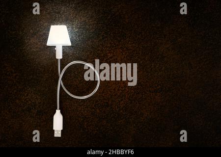 Luminous mobile computer USB LED lamp, close-up on dark background with copy space Stock Photo