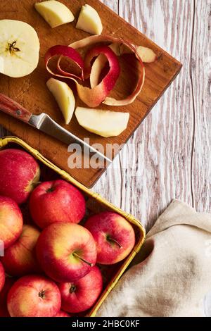 Red apples in a basket and on a cutting board, peeling apples to make a pie Stock Photo