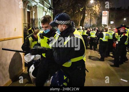 London, UK. 18th Dec, 2021. A police officer is led away by a colleague after the MET moved into to remove a sound system on Whitehall. Thousands of people come out to protest against the latest COVID19 restrictions. Protesters unite for freedom and march through the city to show the government that they do not have faith in their leadership. Credit: Andy Barton/Alamy Live News Stock Photo