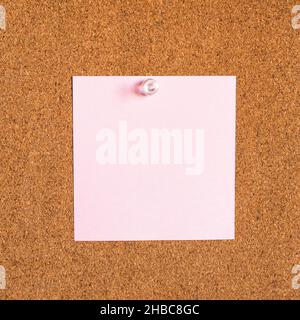 square pink blank note paper pinned to corkboard closeup Stock Photo