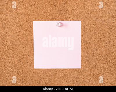 pink blank note paper pinned to cork board closeup Stock Photo