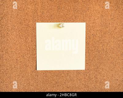 yellow blank note paper pinned to corkboard closeup Stock Photo