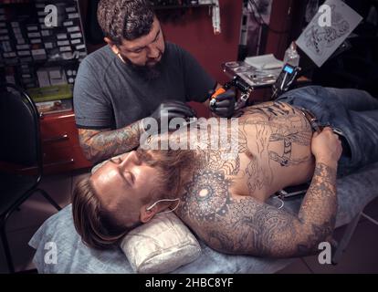 Tattooer making tattoo in salon tattoo parlor Stock Photo