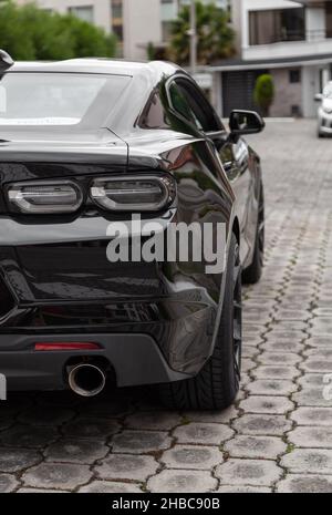 details of the rear of a black sports car, showing the exhaust pipe and taillights, means of transport in the city, lifestyle in the city Stock Photo