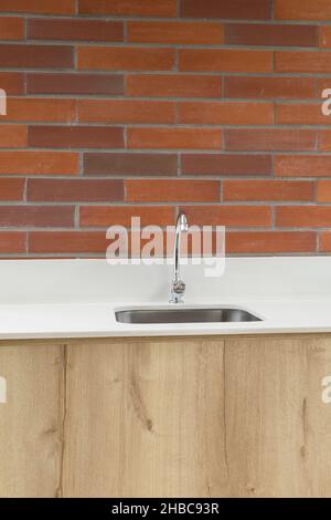 hand basin with a modern tap, space decorated with a brick wall and wooden furniture, interior decoration, style and household objects Stock Photo