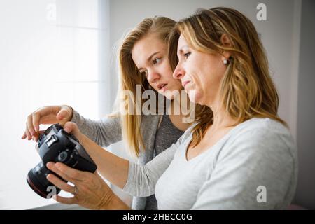 Mother and daughter taking photos and checking them on a modern digital DSLR camera Stock Photo